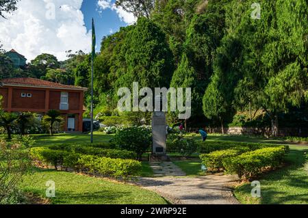 Vista parziale dei verdi giardini di vegetazione di fronte al Palazzo Imperiale di Petropolis nel quartiere Centro durante il pomeriggio estivo cielo azzurro nuvoloso e soleggiato. Foto Stock