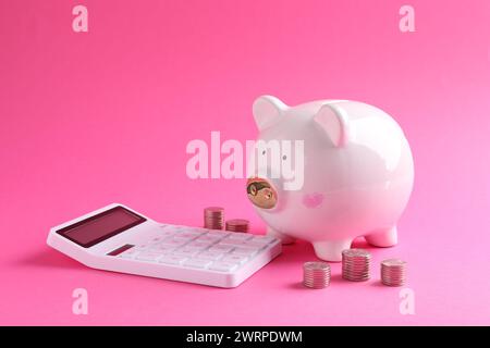 Risparmi finanziari. Salvadanaio, monete e calcolatrice su sfondo rosa Foto Stock