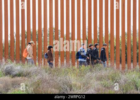 Campo, Stati Uniti. 13 marzo 2024. I migranti camminano lungo il lato degli Stati Uniti del muro di confine con il Messico per arrendersi alla pattuglia di confine degli Stati Uniti vicino a campo, California, il 13 marzo 2024. Un disegno di legge sull'immigrazione bipartisan del Senato per affrontare la questione dell'immigrazione migrante è bloccato nella camera a causa della politica dell'anno elettorale. Foto di Pat Benic/UPI credito: UPI/Alamy Live News Foto Stock