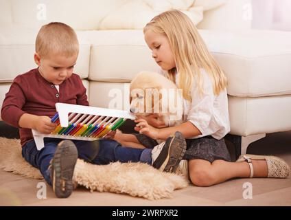 Bambini, cuccioli e giocattoli per bambini in una casa con animali, animali domestici e bambini in un soggiorno. Golden retriever, abaco e divertimento con il cane insieme Foto Stock