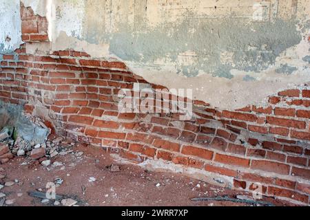 Muro di mattoni in rovina nel vecchio edificio abbandonato distrutto, attenzione selettiva. Agenti atmosferici e degradazione Foto Stock