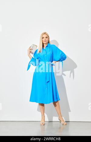 Un look casual luminoso per passeggiate estive. Donna in abito chemisier blu con una borsa argento in mano Foto Stock