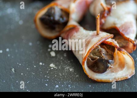 delizioso spuntino a base di fegato di pollo avvolto con pancetta e sale su nero con spazio per copiare Foto Stock