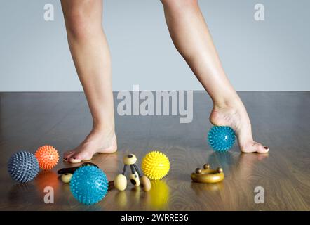 ballerina che massaggia il piede con la palla blu per un massaggio, pavimento in legno Foto Stock