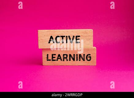 Parole di apprendimento attive scritte su blocchi di legno con sfondo rosa. Simbolo concettuale. Copia spazio. Foto Stock