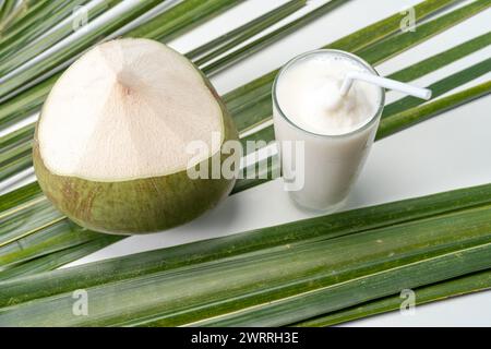 Un bicchiere di dolce profumo di cocco con foglie di cocco. Foto Stock