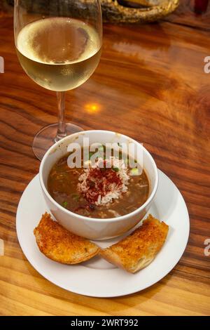 Tazza di gumbo creolo servita con un bicchiere di vino Foto Stock