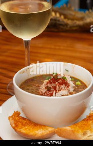 Tazza di gumbo creolo servita con un bicchiere di vino Foto Stock