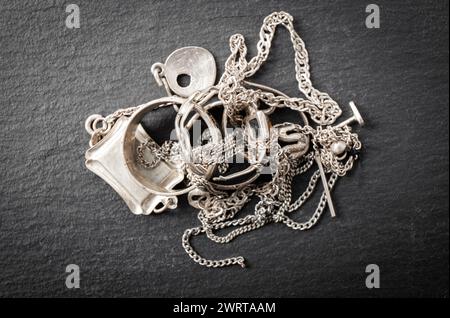 Pile di vecchi rottami in argento, gioielli, anelli, ciondoli, collane a catena, orecchini. Concetto di riciclaggio degli oggetti in argento. Foto Stock