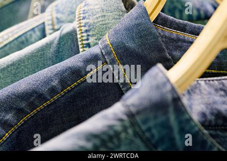 Gruppo di giacche o camicie in denim blu su appendiabiti in un guardaroba Foto Stock