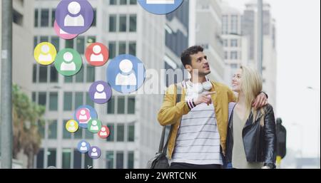 Immagine delle icone dei social media che fluttuano sopra una felice coppia caucasica che cammina e sorride Foto Stock