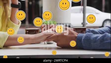Immagine di icone emoji digitali che fluttuano sopra una coppia caucasica che si tiene per mano Foto Stock