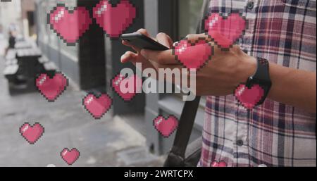 Immagine delle icone del cuore che fluttuano sull'uomo utilizzando lo smartphone Foto Stock