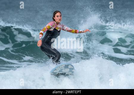 Una surfista che cavalca un'onda al Fistral di Newquay in Cornovaglia nel Regno Unito. Foto Stock