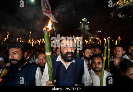 I membri dell'All Assam Students' Union (AASU) prendono parte a una manifestazione fiammeggiante di torce e gridano slogan per protestare contro l'attuazione del Foto Stock