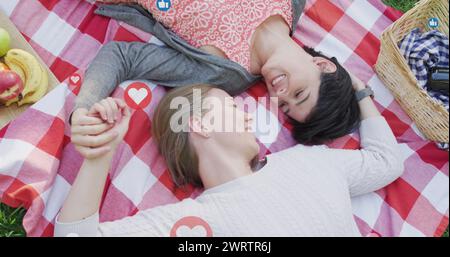 Immagine di cuori e icone simili a quelle di una coppia caucasica che fa un picnic Foto Stock