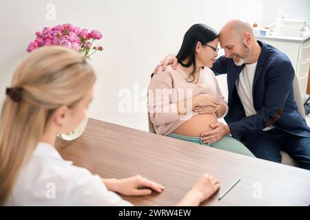 Uomo adulto e sua moglie incinta felice che hanno bambino sano nel grembo materno, controllo gravidanza in clinica privata di ginecologia e riproductologia Foto Stock