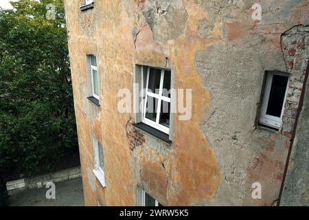 L'angolo del muro dell'edificio è in cattive condizioni, con alcune finestre di plastica di nuova costruzione con vista laterale Foto Stock