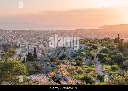 Atene, Grecia - 2 marzo 2024: Paesaggio urbano e mare di Atene al tramonto dalla collina di Filopappo Foto Stock