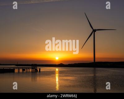 Canale di Hvide Sande con generatore eolico e molo al tramonto sul Mare del Nord, Jutland centrale, Danimarca Foto Stock
