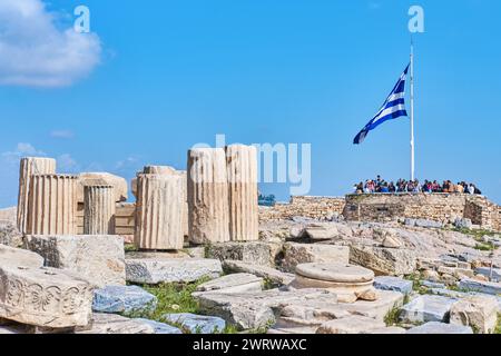 Atene, Grecia - 2 marzo 2024: Enorme bandiera greca che sventola sulla cima del sito dell'Acropoli accanto al Partenone che si affaccia sulla città Foto Stock