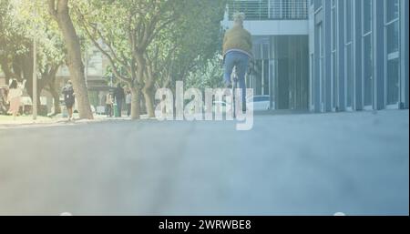 Punti di luce contro la vista posteriore di un uomo in bicicletta per strada Foto Stock