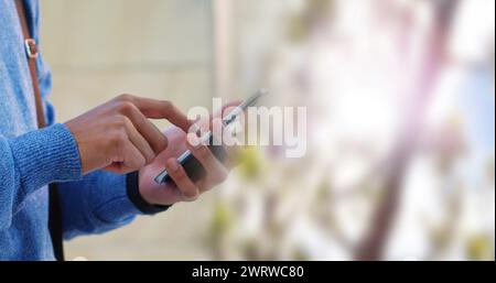 Immagine di un uomo d'affari birazziale che usa lo smartphone su sfondo sfocato Foto Stock