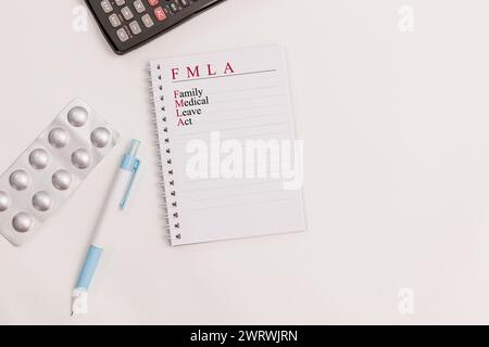 Ambiente di ufficio con notebook con testo "FMLA; Family Medical Leave Act" ben posizionato su una scrivania Foto Stock
