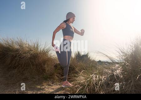 indossate una donna sportiva che controlla il suo orologio smart mentre fate esercizio di stretching delle gambe all'aperto Foto Stock