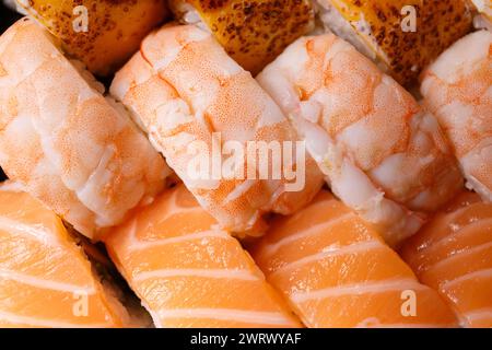 Ampia serie di sushi roll con gamberi, salmone, tonno, vista dall'alto, primo piano. Consegna di sushi. Viene visualizzato come sfondo. Foto Stock