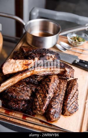 Vari tipi di deliziose e succulente bistecche alla griglia su una tavola di legno in un ristorante. Bistecca di Ribeye, filetto cotto al fuoco. B-B-Q. Foto Stock