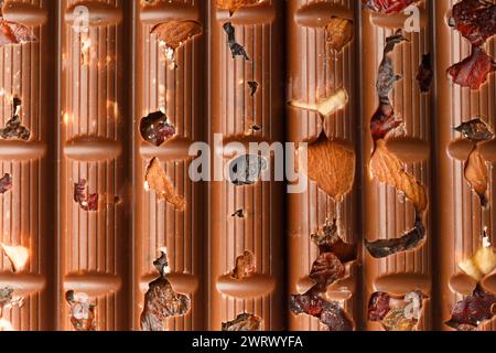 Sfondo cioccolato. Cioccolato al latte con mandorle, uva passa, bacche secche primo piano come sfondo. Foto Stock