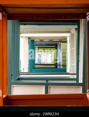 Una vista laterale attraverso la veranda anteriore di una fila di colorate capanne sulla spiaggia Foto Stock