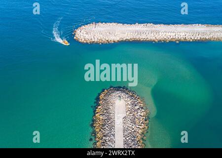 nave che entra in un porto protetto da frangiflutti, vista da un drone Foto Stock