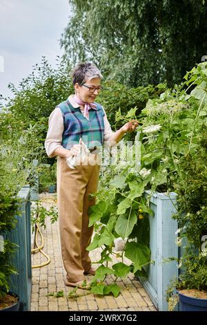 donna matura e sofisticata con capelli corti e un abbigliamento elegante e vivace che si prende cura delle sue piante Foto Stock