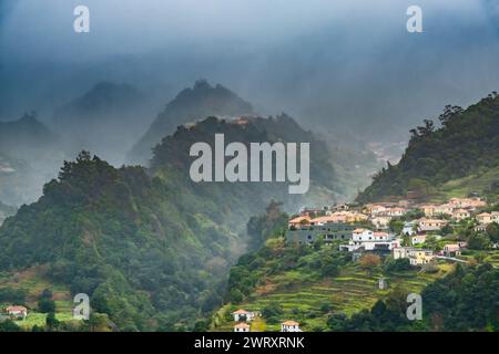 Villaggio tradizionale con terrazza Sao Vicente, Isola di Madeira, Portogallo. Piccole case e giardini in un verde paesaggio montano con il tempo tempestoso. Foto Stock