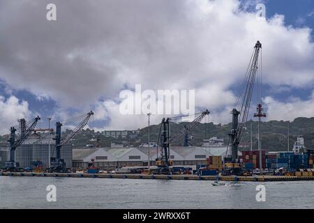 Cartagena, Colombia - 25 luglio 2023: Enormi silos e grandi magazzini a Isla Diablo in porto sotto uno spesso paesaggio nuvoloso con patch blu. Gru e contenimento Foto Stock