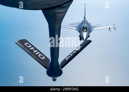 Un KC-135 Stratotanker con il 121st Air Refueling Wing rifornisce un F-16 Fighting Falcon, assegnato al 113th Wing, sull'Oceano Atlantico, il 12 marzo 2024. L'F-16 Fighting Falcon può volare per oltre 500 miglia, ma il KC-135 può estendere il suo raggio oltre questo e fornire potenza aerea ovunque e in qualsiasi momento a livello globale. (Foto della U.S. Air National Guard del Senior Airman Ivy Thomas Foto Stock