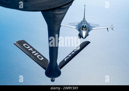 Un KC-135 Stratotanker con il 121st Air Refueling Wing rifornisce un F-16 Fighting Falcon, assegnato al 113th Wing, sull'Oceano Atlantico, il 12 marzo 2024. L'F-16 Fighting Falcon può volare per oltre 500 miglia, ma il KC-135 può estendere il suo raggio oltre questo e fornire potenza aerea ovunque e in qualsiasi momento a livello globale. (Foto della U.S. Air National Guard del Senior Airman Ivy Thomas) Foto Stock