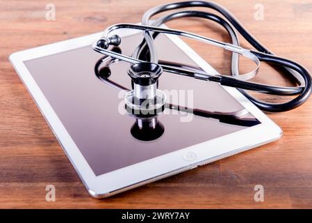 stetoscopio medico e tavoletta su sfondo di legno marrone. Concetto di assistenza sanitaria. fonendoscopio. Foto Stock