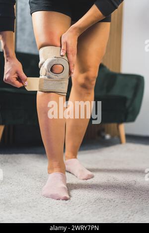 primo piano verticale di una donna che applica un sostegno protettivo al ginocchio, concetto di assistenza sanitaria. Foto di alta qualità Foto Stock