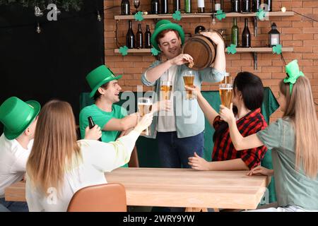 I giovani con la birra spillata dalla botte ai suoi amici nel bar di St. Patrick's Day Foto Stock