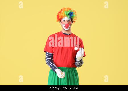 Ritratto di clown giocolieri su sfondo giallo. Festa del giorno dello scemo d'aprile Foto Stock