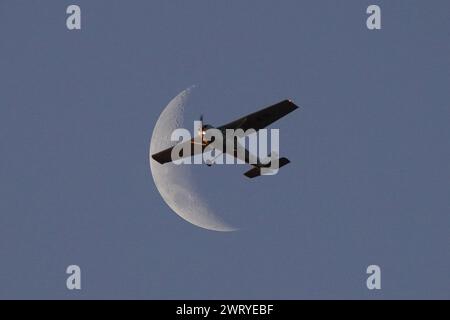 Santiago, metropolitana, Cile. 14 marzo 2024. Un piccolo aereo passa davanti alla luna crescente a Santiago, Cile. (Immagine di credito: © Matias Basualdo/ZUMA Press Wire) SOLO PER USO EDITORIALE! Non per USO commerciale! Foto Stock