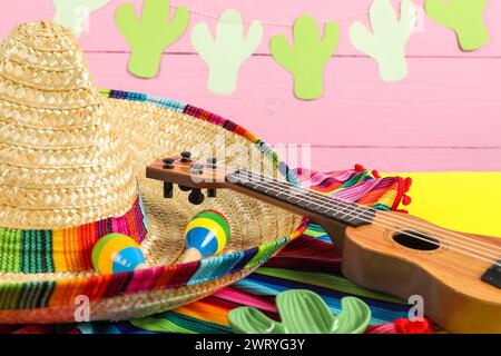 Cappello sombrero messicano, ukulele e maracas su tavola gialla, primo piano Foto Stock