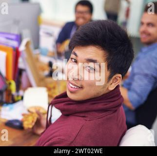Uomo d'affari, ritratto e ristorante con sorriso in ufficio per la pausa pranzo, pizza e compagnia di coworking. Programmatore, dipendente asiatico e volto o felicità Foto Stock