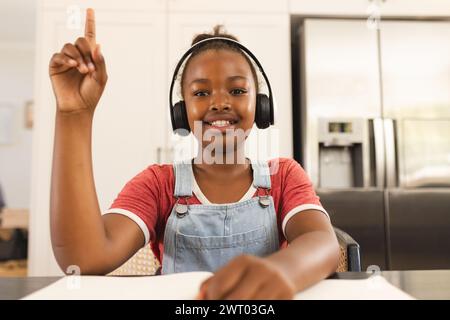 Una giovane ragazza afroamericana alza la mano durante una lezione di videochiamata online Foto Stock