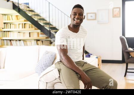 Un giovane afroamericano è seduto e brilla di gioia a casa Foto Stock