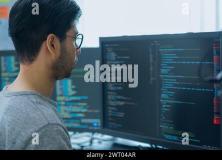 App asiatica di codifica per sviluppatori di ingegneri tempestivi con dati software posizionati di fronte al monitor del computer in ufficio Foto Stock