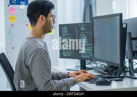 App asiatica di codifica per sviluppatori di ingegneri tempestivi con dati software posizionati di fronte al monitor del computer in ufficio Foto Stock